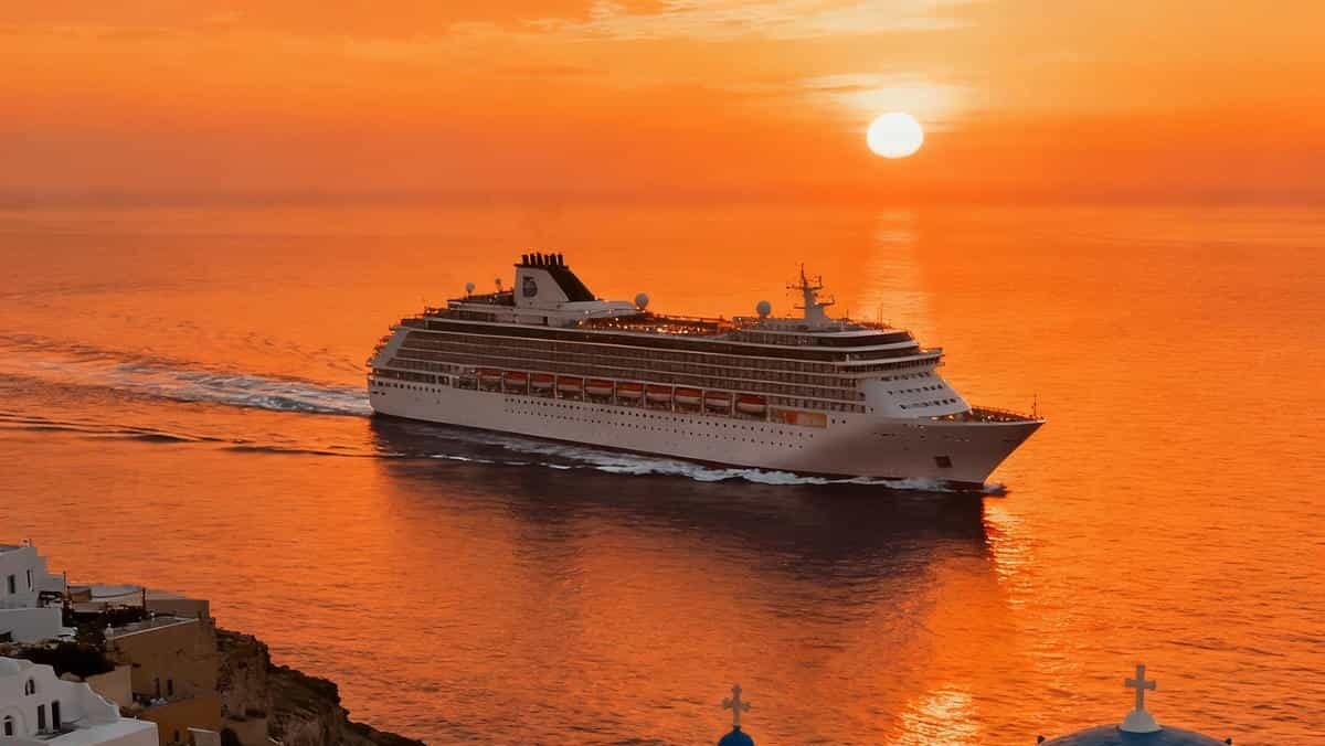 Cruise ship sailing past Santorini’s whitewashed buildings at sunset
